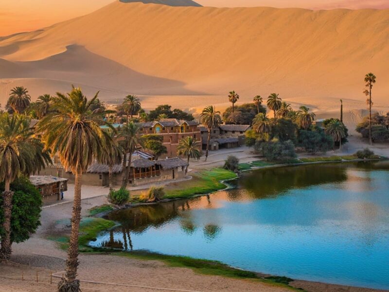 The Huacachina oasis surrounded by palm trees and sand dunes in Ica