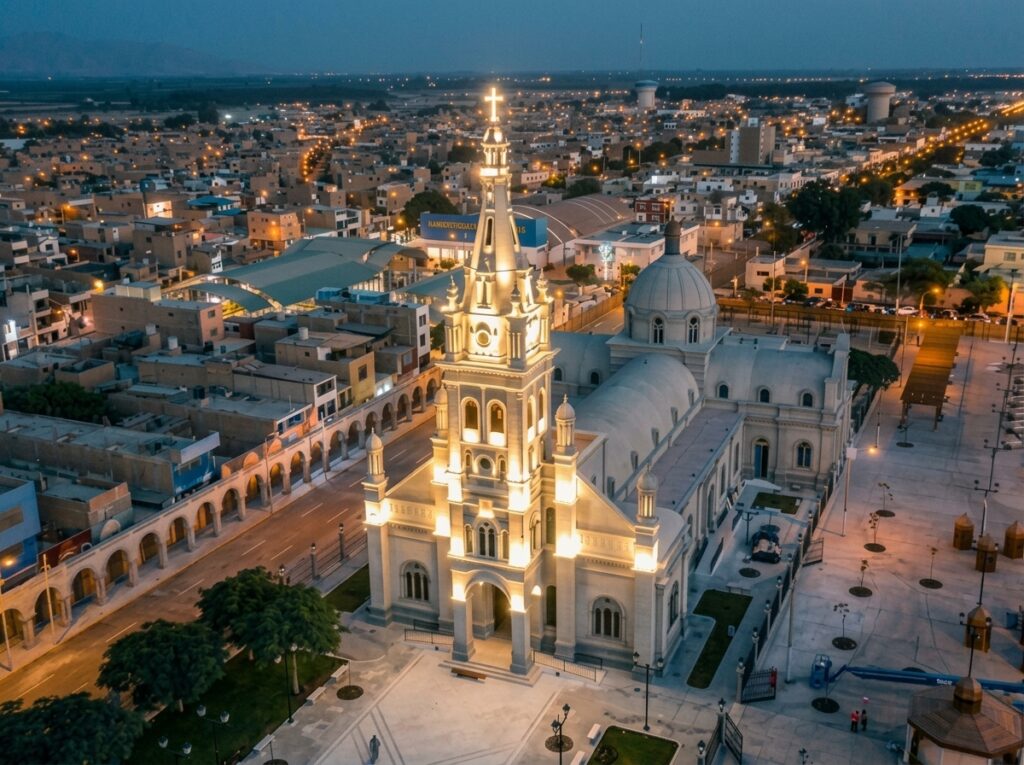 Aerial view of the illuminated Señor de Luren Sanctuary at dusk, with the city of Ica, Peru, spreading out behind it