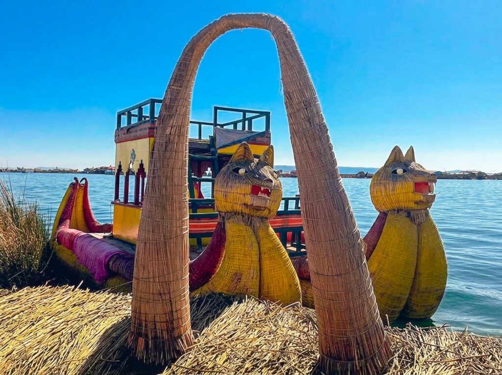 Traditional totora reed boat with carved puma heads moored at a Uros floating island on Lake Titicaca near Puno, Peru