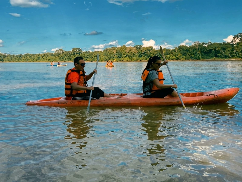 Turistas remando en kayaks amarillos sobre las mansas aguas del rio Tambopata