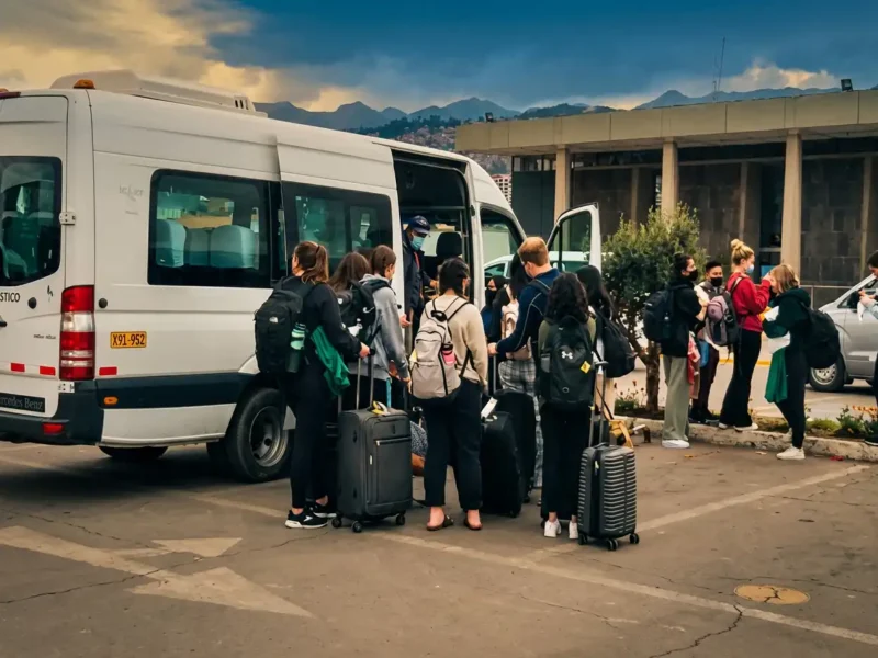 Grupo de turistas bajando de la van con sus maletas en el aeropuerto
