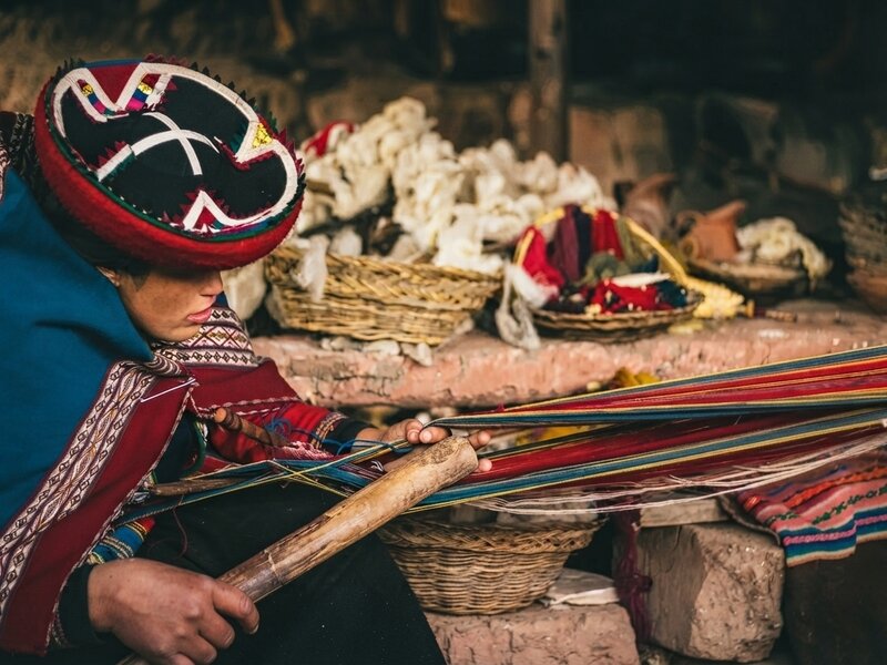 Mujeres locales mostrando el proceso tradicional de tejido con tintes naturales en Chinchero.