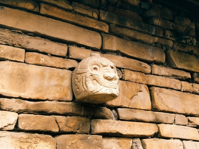 Detalle de una escultura de piedra con rostro felino en la pared exterior del templo de Chavín