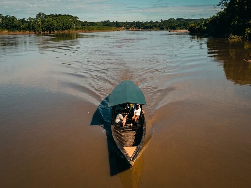 Bote de madera navegando por el rio Tambopata rodeado de selva