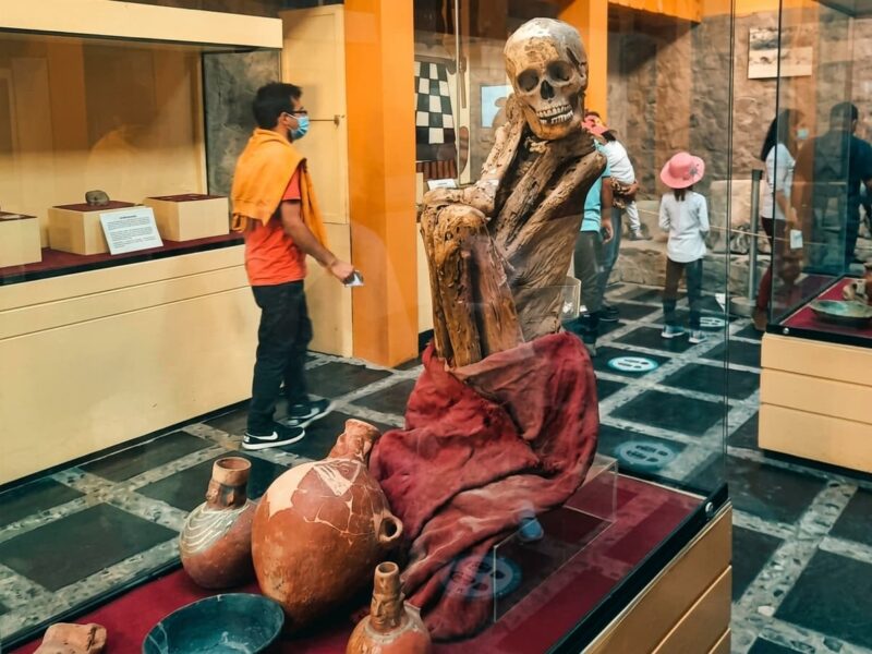 Fardo funerario y vasijas de cerámica de la cultura Wari exhibidos en vitrina del Museo de Sitio en Ayacucho, Perú