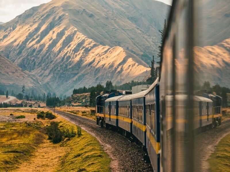 Tren turístico de ventanas panorámicas cruzando el exuberante paisaje montañoso hacia Aguas Calientes.