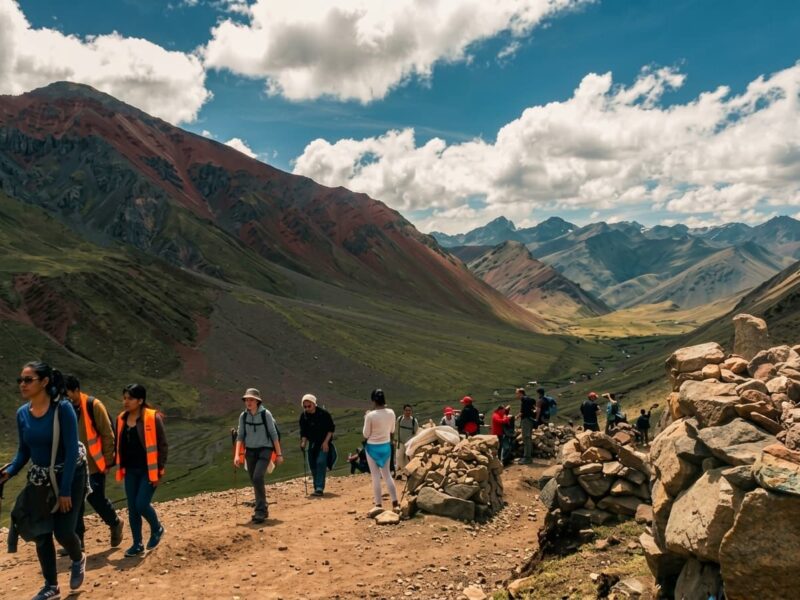 Grupo de senderistas equipados caminando en fila por el sendero de montaña hacia la cumbre de Vinicunca.