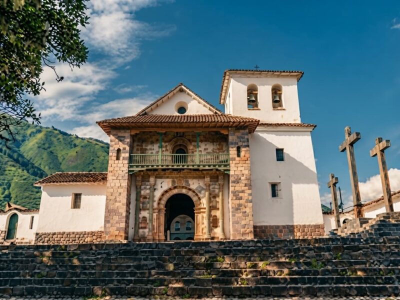 Exterior de la histórica iglesia colonial de Andahuaylillas con su plaza de árboles tradicionales.