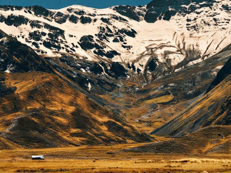 Letrero del punto geográfico La Raya con picos nevados y cordillera andina de fondo.
