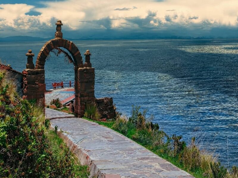 Camino empedrado en la Isla Taquile con arco de piedra tradicional y vista al Lago Titicaca.