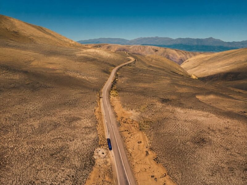 Carretera asfaltada cruzando la llanura andina del altiplano peruano bajo un cielo despejado.