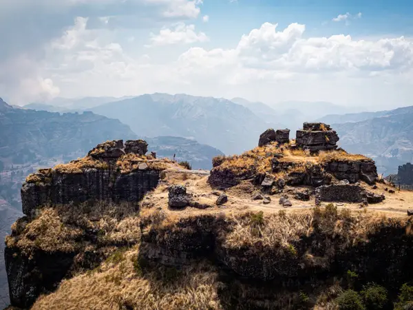 Cima rocosa de Waqrapukara con restos de muros incas entre las agujas de piedra y montañas andinas al fondo