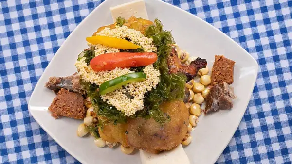 Plato de chiriuchu servido sobre mantel a cuadros, con tortilla, cochayuyo, carnes, embutidos, queso, maíz tostado y tiras de rocoto y ají