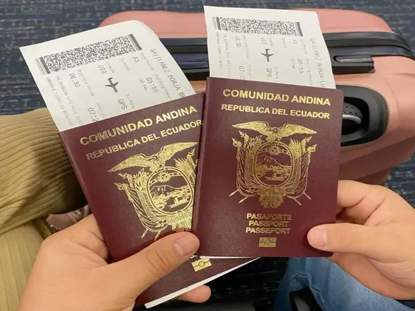 Dos pasaportes de Ecuador de la Comunidad Andina sostenidos junto a tarjetas de embarque sobre una maleta
