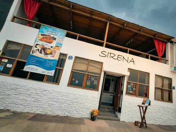 Fachada blanca del restaurante La Sirena en Chorrillos, con balcón de madera y cortinas rojas