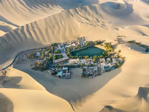 Huacachina oasis lagoon surrounded by palm trees and sand dunes near Ica