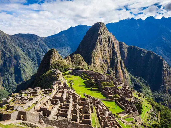 Clear view of Machu Picchu and Huayna Picchu with white clouds over the mountains in a shoulder month
