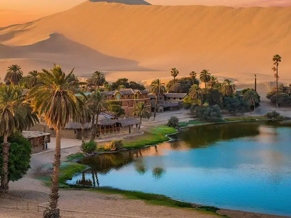The Huacachina oasis surrounded by palm trees and sand dunes near Ica