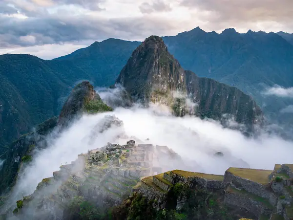 Morning cloud rising over the Machu Picchu citadel with Huayna Picchu appearing above the mist