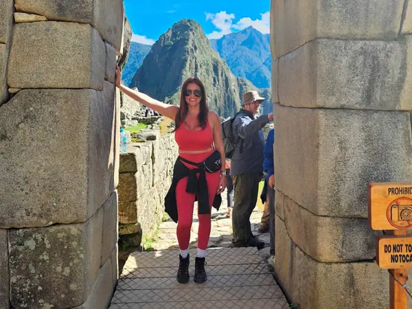 Traveller standing in an Inca doorway inside the urban sector of Machu Picchu, with Huayna Picchu behind