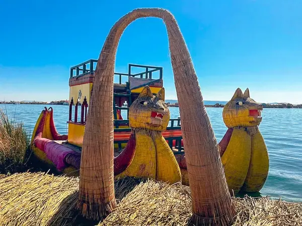 Traditional totora reed boat with carved puma heads moored at a Uros floating island on Lake Titicaca near Puno