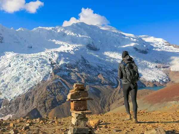 Travellers at the summit of Vinicunca with the snow-capped Ausangate range behind